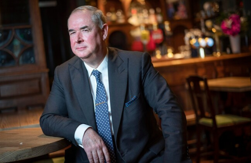 Sir Geoffrey Cox leaning on a bar table, looking pensive.